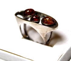 This is beautiful vintage 1990s Baltic Sea Genuine Amber ring hand set in 925 sterling silver in Poland.   The colors might look slightly different on the pictures. Sizes available: 6.5, 7, 7.25 and 7.5; size of silver setting 1.25 x 0.4''; amber stones 0.2-0.3''; weight 6.2G. Handmade in Poland and ship from Texas USA. Amber is the fossilized, hardened resin of trees, ranging in age from less than a million to more than 300 million years old. This beautiful Baltic Amber has been popular throughout the World for Centuries and is reflected in many of the regions folk tales. Amber Jewels are actually pieces of petrified tree sap and found in only three areas throughout the World. Occasionally, you may find pieces of insects or plants trapped inside these jewels but they are quite rare. Amber Retro Silver Rings For Collectors, Retro Silver Rings For Anniversary, Silver Retro Rings For Anniversary, Silver Retro Anniversary Rings, Retro Silver Rings For Formal Occasions, Retro Style Silver Rings For Formal Occasions, Vintage Amber Hallmarked Rings, Vintage Amber Rings For Anniversary, Antique Jewelry Rings