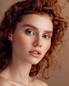 a woman with freckled hair and blue eyes looks at the camera while posing for a portrait