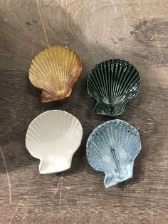 four seashells sitting on top of a wooden table next to eachother