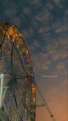 a ferris wheel is lit up at night with the moon in the sky behind it