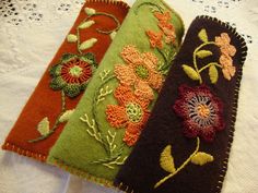 three different colored flowers are sitting on a white table cloth, one is green and the other is red