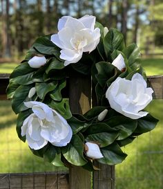 a wreath with white flowers hanging on a fence