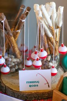 fishing rods are displayed in glass vases with paper tags on them and some sticks sticking out of the top