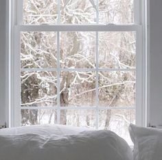 a bed sitting in front of a window covered in snow