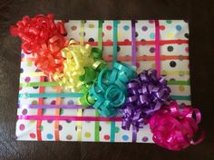 colorful bows and ribbons are tied on wrapped gift boxes with polka dot wrapping paper in rainbow colors