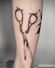 a tattoo on the leg of a person with scissors