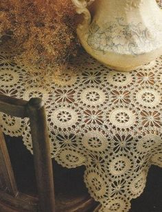 an antique vase and table cloth on a wooden chair with a lace doily over it