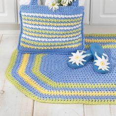 a crocheted bag and slippers are sitting on the floor next to flowers