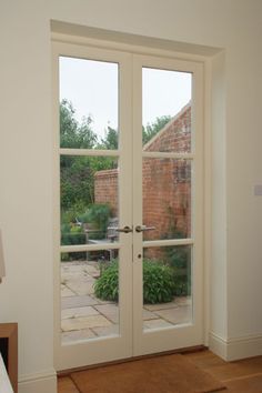 an empty room with two doors leading to a patio and brick building in the background