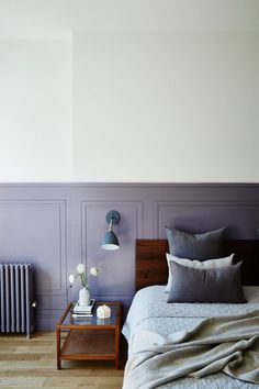 a bedroom with purple walls and wood flooring in the corner, along with a wooden side table