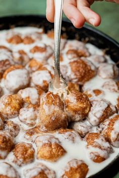 a person is spooning some sugar covered doughnuts