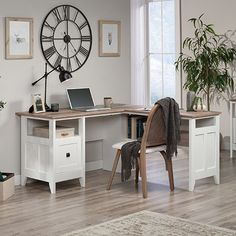 a desk with a laptop on it in front of a clock and potted plants