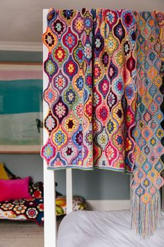 a multicolored crocheted blanket hanging from the side of a bunk bed