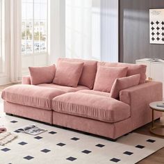 a pink couch sitting on top of a rug in a living room next to a window