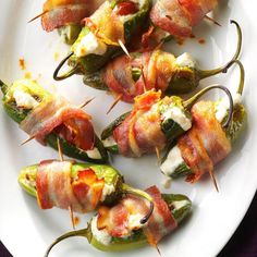 bacon wrapped jalapenos on a white plate with toothpicks and cheese