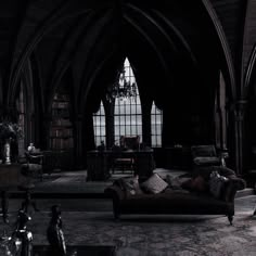 a living room filled with lots of furniture next to tall arched windows in an old building