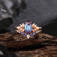 an image of a ring that is on top of a piece of wood with rocks in the background