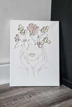 a drawing of a woman's face with flowers in her hair on a white canvas