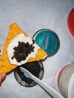 a person holding a piece of food with black cavias on it and a spoon