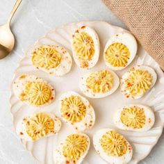 deviled eggs are arranged on a white plate with gold spoons next to it