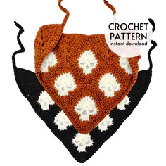 an orange and black crocheted bib with white flowers on the front, attached to a hook