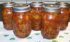 four jars filled with pickles sitting on top of a table