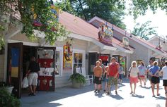 many people are walking down the sidewalk in front of shops