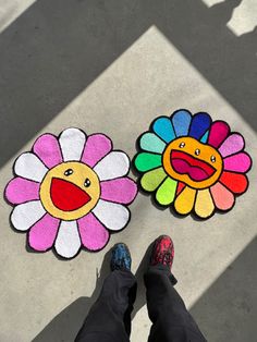 two flower shaped rugs on the ground with someone's feet standing next to them