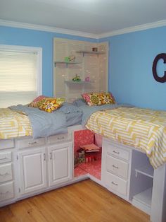 two beds in a room with blue walls and white cupboards next to each other