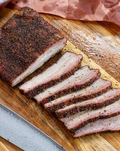 sliced meat sitting on top of a cutting board next to a knife