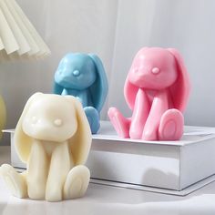 three colorful elephant figurines sitting on top of a white box next to a lamp