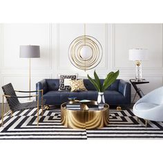 a living room with black and white rugs, gold accents and blue couches