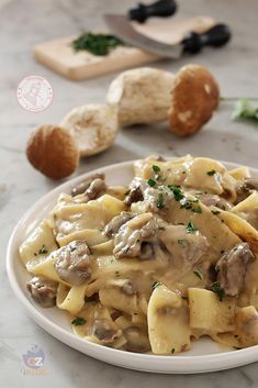 a white plate topped with pasta covered in mushroom sauce