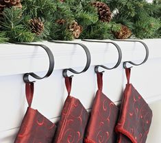 three christmas stockings hanging from hooks on a mantle