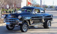 an old black car is parked on the street