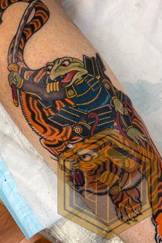 a tiger tattoo on the leg of a man with an orange and black tiger design