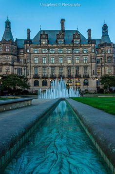 a large building with a fountain in front of it and grass on the ground next to it