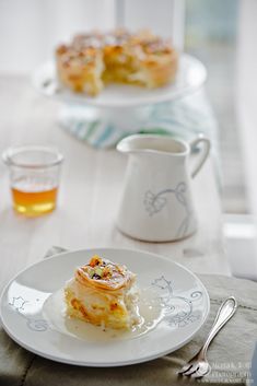 a white plate topped with food on top of a table next to cups and saucers