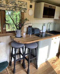 two stools are in front of the kitchen counter and bar area with a potted plant on it