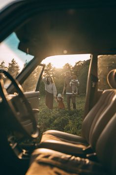 two people are standing in the back seat of a car, one is holding a baby