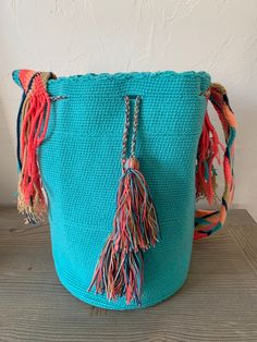 a blue bag with tassels on it sitting on top of a wooden table