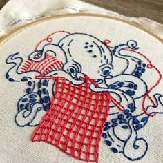 an embroidery project with red and blue designs on white fabric, featuring octopus in checkered dress