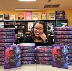 a woman sitting at a table in front of stacks of books with the title, blood marked