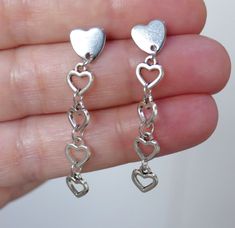 "Dull silver tone small heart charm earrings. Small heart charms dangling from stainless steel heart earring studs. Earring length: 44mm; 1.7\" (from end to end) Earring stud material: 316 stainless steel Charm material: Zinc alloy, Nickel safe, Lead free This listing is for one pair of heart earrings with rubber backs. These earrings will come in a gift bag. I offer combined shipping costs which give you a shipping discount for ordering multiple items from my shop. Earrings care: Take them off Silver Heart Dangle Earrings, Heart Earring, Earring Stud, Heart Dangle Earrings, Earring Studs, Earrings Small, Heart Earrings Studs, Small Heart, Jewelry Inspo