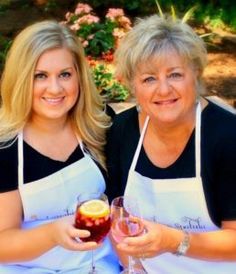 two women in aprons holding wine glasses