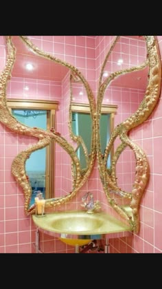 a bathroom with pink tiles and gold accents on the walls, along with a sink