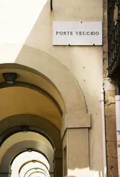 a man walking down an alley way under a sign that reads ponte vecchio