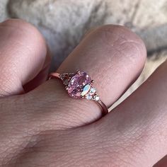 a woman's hand with a pink diamond ring on her left hand and the other hand holding an engagement ring