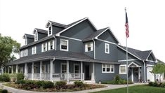 a large gray house with an american flag in the front yard