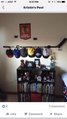 there are many hats hanging on the wall above a book shelf with cds and dvds